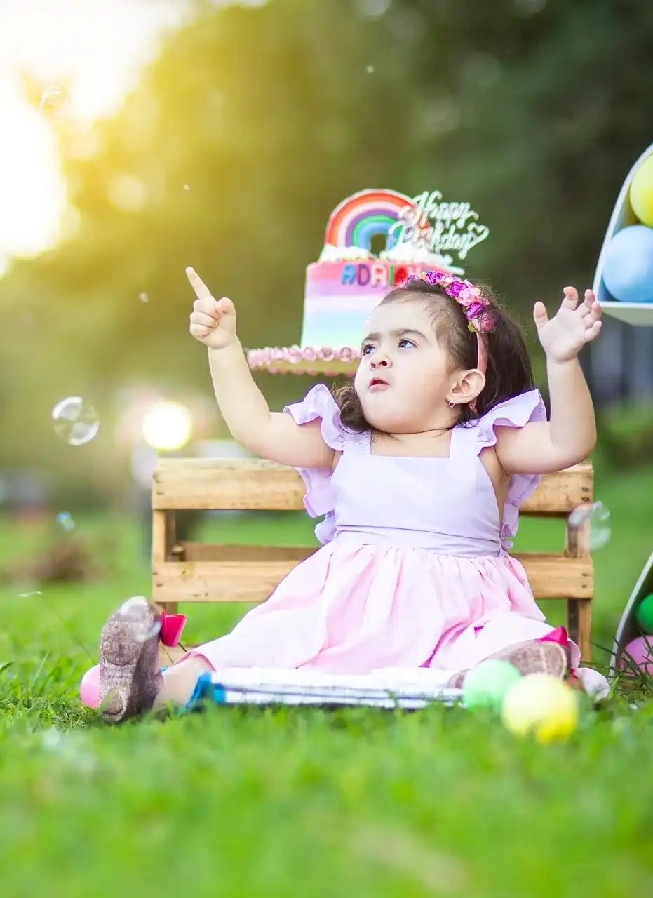 A joyful toddler celebrating her colorful birthday outdoors with bubbles and cake, captured in a magical moment by Tanmay Events in Thrissur