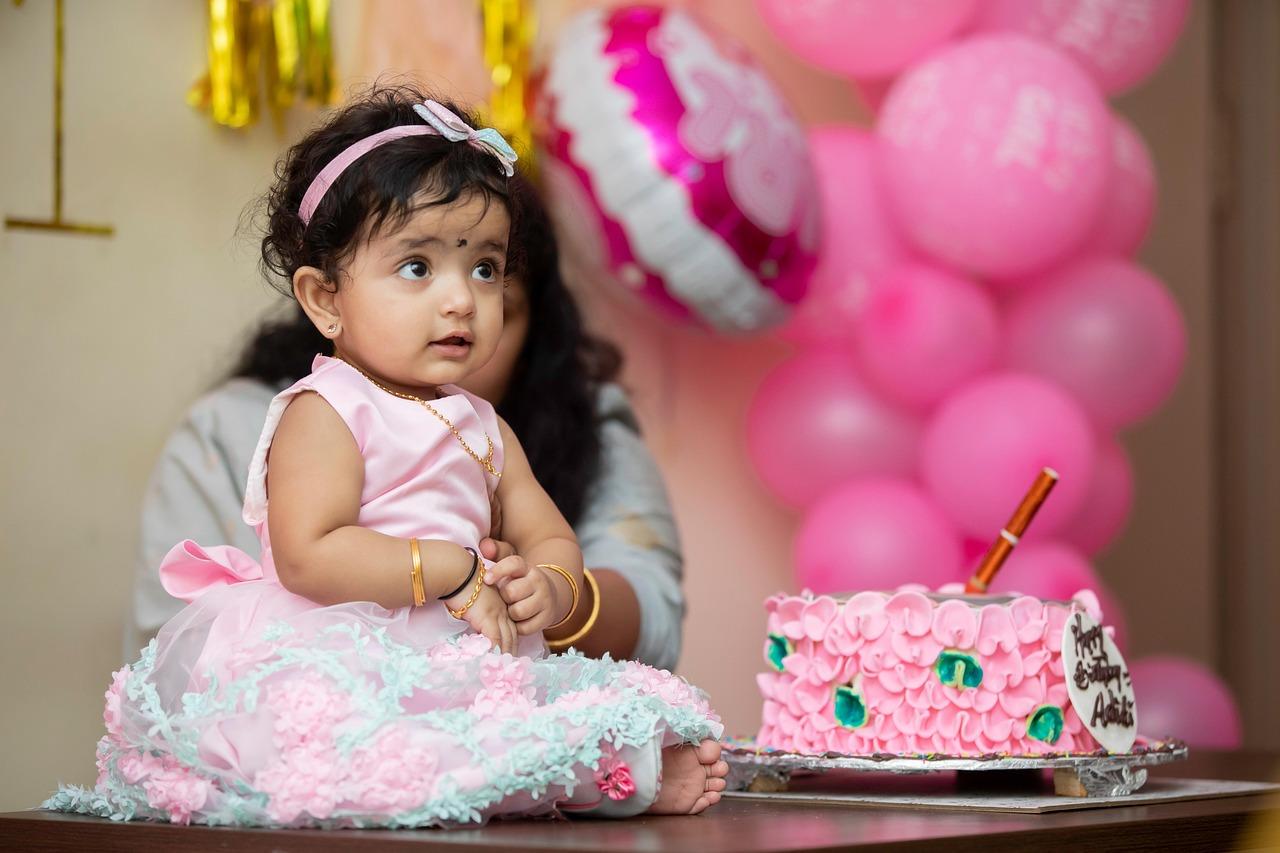 A joyful toddler celebrating her colorful birthday outdoors with bubbles and cake, captured in a magical moment by Tanmay Events in Thrissur